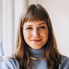 Smiling woman with bangs and a blue turtleneck.